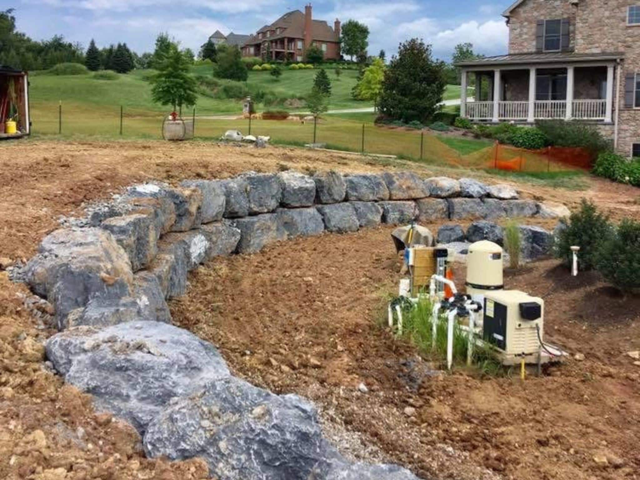A retaining wall made of large grey rocks under construction