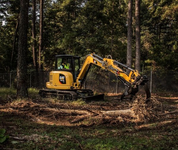 Yellow mini excavator removing tree roots