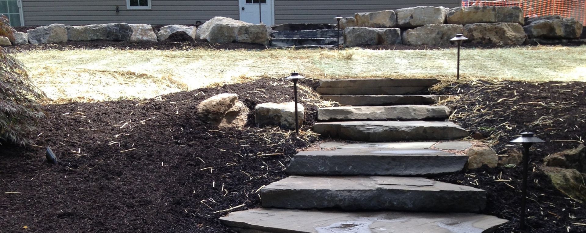 A landscaped yard with stone steps and a retaining wall