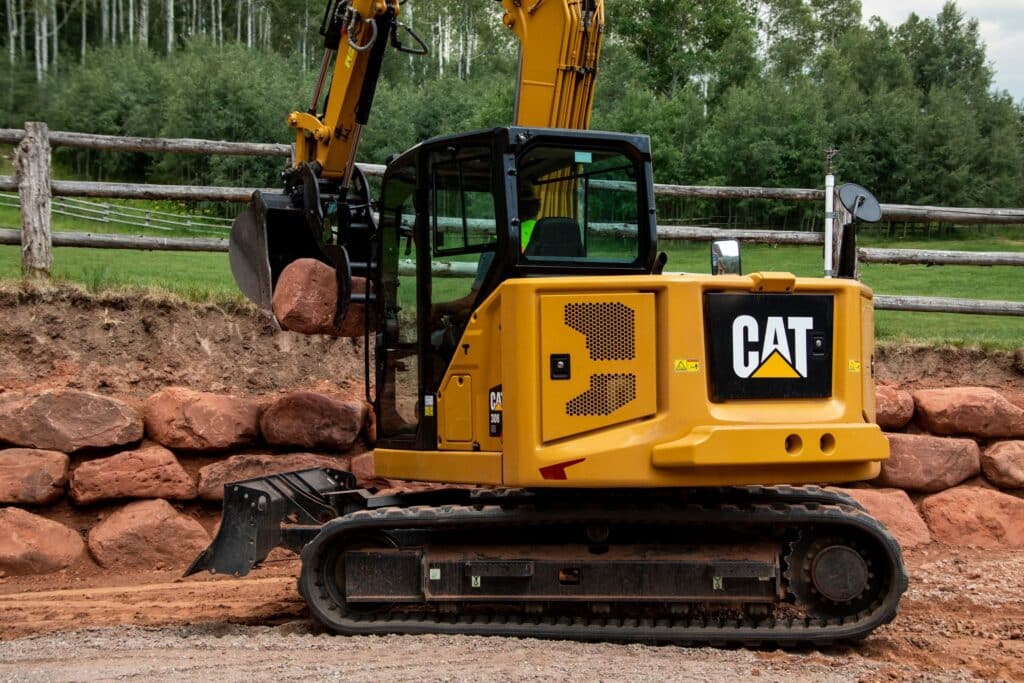 A Cat 308 CR mini excavator moving rocks