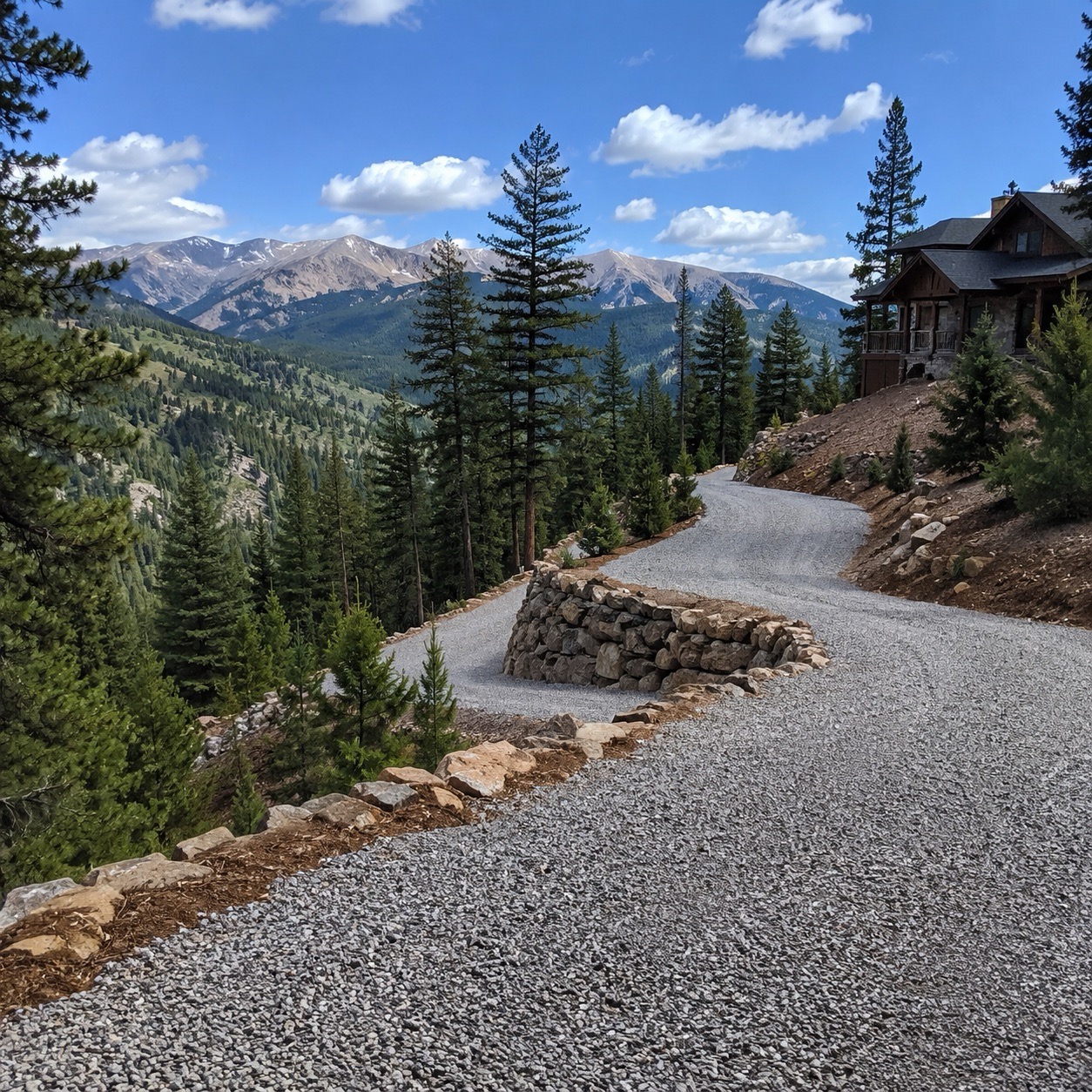 Mountain gravel driveway with stone retaining wall.