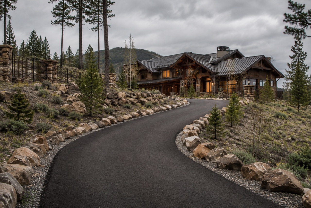 Winding asphalt driveway leading to a large mountain home.