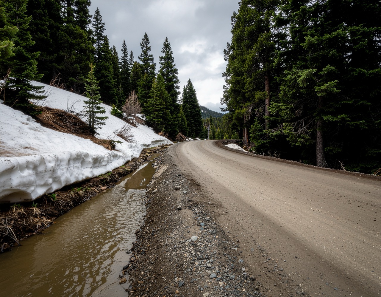 Melting snow flowing into a mountain roadside ditch.